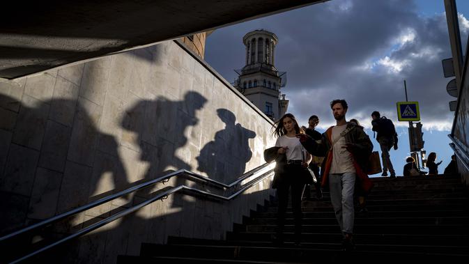 Orang-orang berjalan ke underpass di bawah jalan saat matahari terbenam di Moskow, Rusia, Selasa (15/9/2020). (AP Photo / Alexander Zemlianichenko)