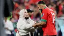 Pemain Maroko, Sofiane Boufal, merayakan kemenangan atas Portugal bersama ibunya pada laga perempat final di Stadion Al-Thumama, Sabtu (10/12/2022). (AFP/Karim Jaafar)