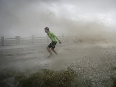 Seorang pria berusaha berlari saat gelombang ombak besar menerjang Wanning akibat Topan Sarika di provinsi Hainan, Tiongkok, (18/10). (REUTERS/Stringer)