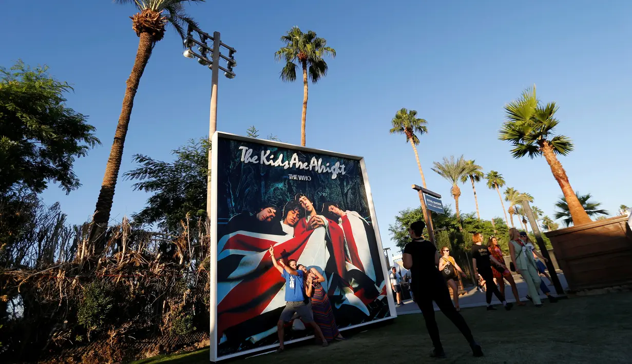 Penonton berpose di depan papan iklan album "The Kids Are Alright" band The Who dalam acara Desert Trip di Empire Polo Club di Indio, California, AS (8/10). The Who salah satu band legendaris yang tampil di Desert Trip 2016. (REUTERS/Mario Anzuoni)