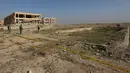 Pasukan Kurdi berdiri di sekitar kuburan massal yang diduga lokasi makam anggota Yazidi Irak di pinggiran kota Sinjar, 30 November 2015. Pasukan Kurdi menemukan kuburan ini usai berhasil merebut kembali kota Irak dari militan ISIS. (Reuters/Ari Jalal)