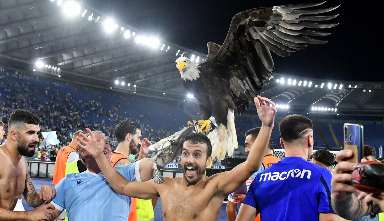 Tak mau ketinggalan, mantan pemain AS Roma yang kini berseragam Lazio yakni Pedro pun ikut merayakan kemenangan bersama burung Elang di depan para pendukung Biancocelesti yang bersorak. (AFP/Vincenzo Pinto)