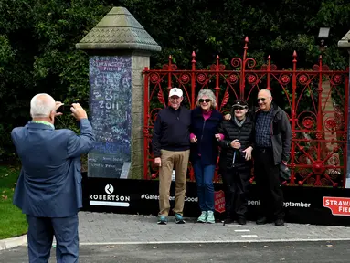 Pengunjung berpose di depan gerbang  Strawberry Fields yang baru dibuka untuk umum di Liverpool, Rabu (18/9/2019). Strawberry Field menjadi salah satu tempat ikonis ketika John Lennon menulis lagu The Beatles “Strawberry Fields Forever” dalam album Sgt.pepper Lonely Hearts Club Band (Paul ELLIS/AFP)