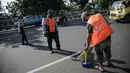 Petugas Dishub mengawasi pelanggar aturan Pembatasan Sosial Berskala Besar saat menyapu jalan di Tanah Abang, Jakarta, Jumat (15/5/2020). Pemprov DKI memberlakukan sanksi sosial bagi pelanggar PSBB dengan memakaikan rompi bertulis ‘Pelanggar PSBB’ saat menyapu jalan. (Liputan6.com/Faizal Fanani)