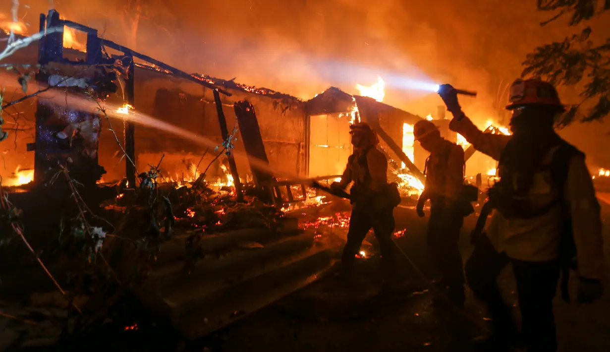 Petugas pemadam kebakaran berjuang memadamkan kobaran api di sebuah rumah di Malibu, California, AS, Jumat (9/11). Api Woolsey pertama kali dilaporkan terdeteksi dekat Thousand Oaks. (AP Photo/Ringo H.W. Chiu)