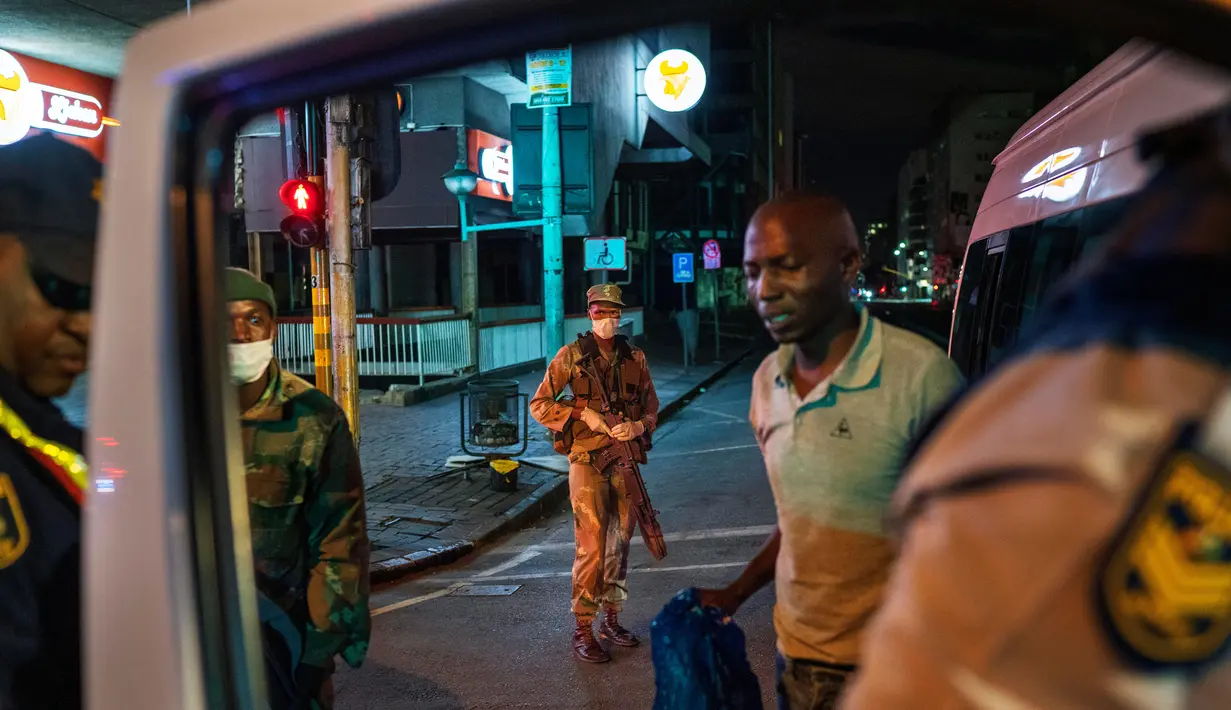 Pasukan Pertahanan Afrika Selatan dan polisi memeriksa pengemudi minibus yang melanggar lockdown di pusat kota Johannesburg, Afrika Selatan, Jumat (27/3/2020). (AP Photo/Jerome Delay)