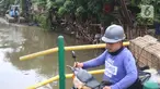 Warga melintas saat alat berat dioperasikan untuk pengerukan di Kali Mampang, Pondok Jaya, Sabtu (19/2/2022). Pengadilan Tata Usaha Negara (PTUN) Jakarta mengabulkan gugatan warga pada 19-21 Februari 2021 terkait program pencegahan banjir yang dilakukan Pemprov DKI. (Liputan6.com/Herman Zakharia)