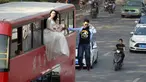 Pesulap Lei Xin (kanan) berada di luar bus tingkat sambil melayang dengan seorang wanita bergaun pengantin di Zhengzhou, Provinsi Henan, China, (15/10/2015). Aksi bertujuan mengajak masyarakat untuk tidak takut menikah diusia muda. (REUTERS/Stringer)