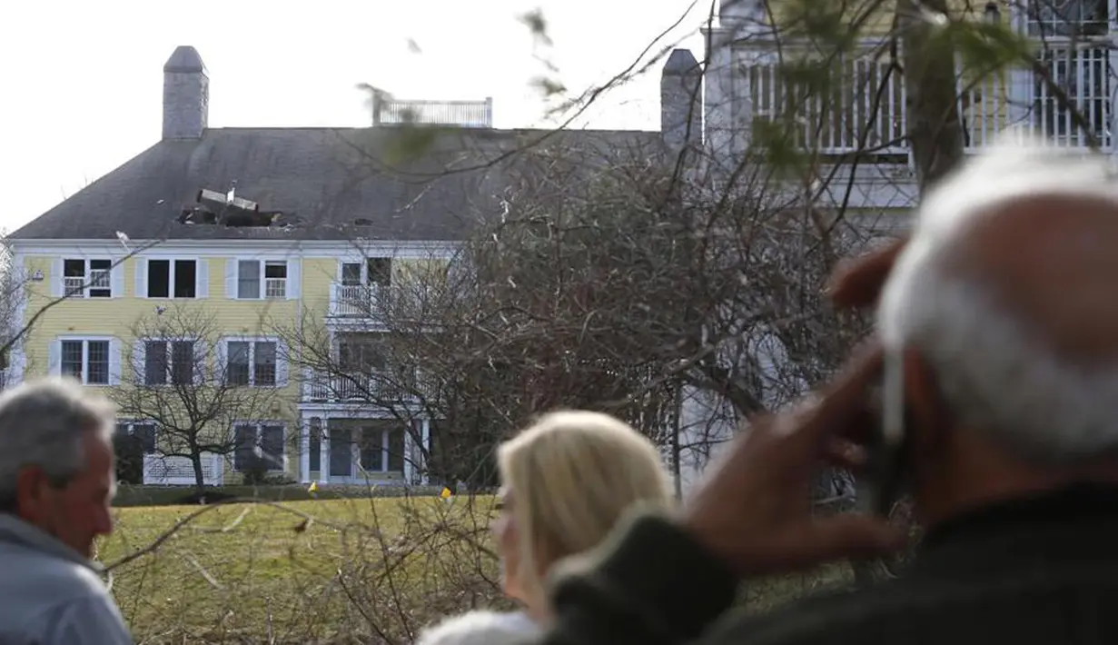 Sejumlah warga menyaksikan pesawat ringan bermesin satu yang menabrak atap kondominium di Methuen, Massachusetts, (1/3). Dalam kejadian ini pilot pesawat tewas. (bostonglobe.com)