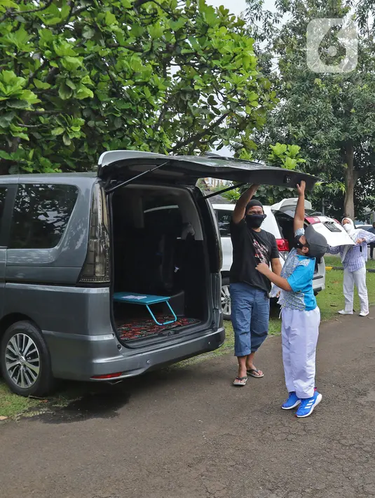 Murid menutup bagasi mobil seusai mengikuti Drive in Learning (DRIL) dengan konsep pembelajaran di ruang terbuka di Jakarta, Senin (5/4/2021). Kegiatan tersebut dilakukan guna menghidupkan semangat belajar siswa dengan tetap mengikuti protokol kesehatan secara ketat. (Liputan6.com/Herman Zakharia)