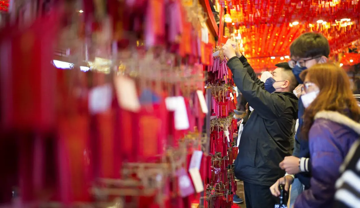 Seorang pria memasang kantong merah pada dinding Kuil Hongludi Nanshan Fude untuk menandai hari ketiga Tahun Baru Imlek di New Taipei City, Taiwan, Selasa (24/1/2023). (Sam Yeh/AFP)