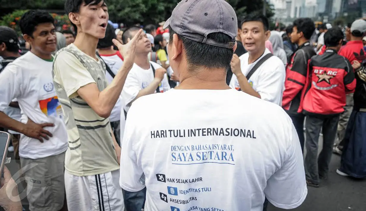 Seorang warga belajar bahasa isyarat kepada penyandang disabilitas tuna rungu di arena Car Free Day, Jakarta, Minggu (25/9). Sosialisasi bahasa isyarat itu sebagai salah satu kampanye memperingati Hari Tuli Internasional. (Liputan6.com/Faizal Fanani)