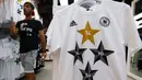 Salah satu petugas toko di Frankfurt, (14/7/2014), melintas diantara kaos-kaos berlogo federasi sepak bola Jerman dengan empat bintang. (REUTERS/Ralph Orlowski)