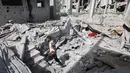 Seorang pria Palestina berjalan di antara reruntuhan bangunan di daerah yang menjadi sasaran serangan Israel di Khan Yunis di Jalur Gaza selatan, pada 2 April 2025. (Eyad BABA/AFP)
