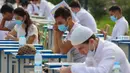 Para siswa Uzbekistan mengikuti ujian masuk luar ruangan, di tengah pandemi COVID-19 yang sedang melanda, di Tashkent pada Rabu (2/9/2020). (Photo by Yuri KORSUNTSEV / AFP)
