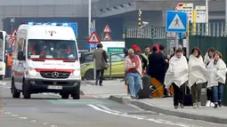 Calon penumpang mengenakan selimut berjalan meninggalkan lokasi ledakan di Bandara Zaventem dekat Brussels, Belgia, (22/3). Sedikitnya 13 orang tewas akibat ledakan beruntun yang mengguncang ruang keberangkatan bandara. (REUTERS / Francois Lenoir)