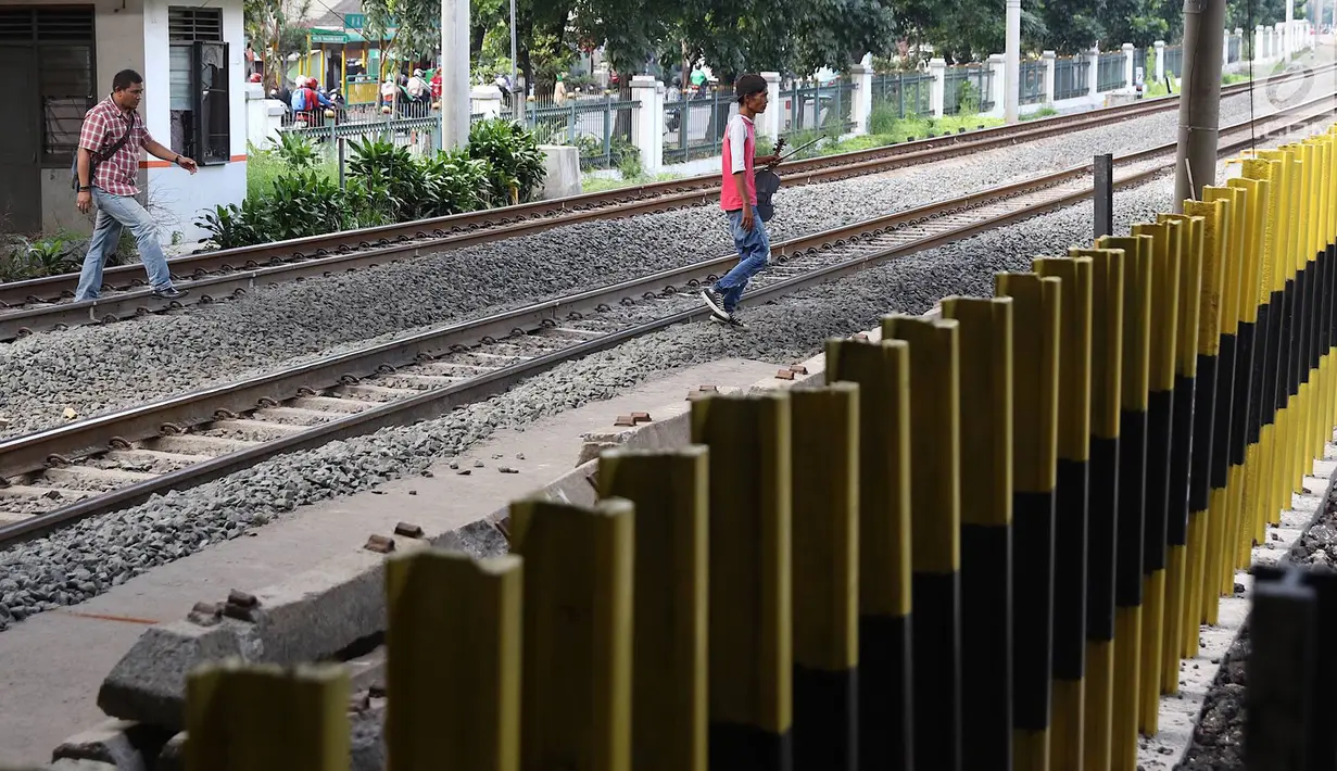 Pejalan kaki menyeberangi perlintasan kereta api di Tanjung Barat, Jakarta, Senin (7/1). Meskipun sering terjadi kecelakaan dan dipasangi pagar, pejalan kaki tetap melompati pagar dari pada menggunakan fasilitas JPO. (Liputan6.com/Immanuel Antonius )