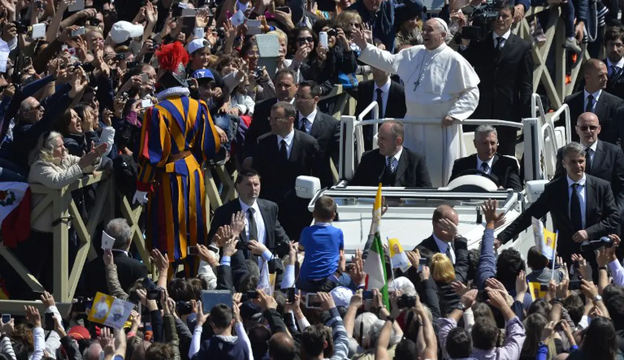 Minggu (20/4/2014), usai Misa Paskah, Paus Fransiskus menyapa kerumunan umat yang hadir di Lapangan Santo Petrus. (AFP PHOTO/ANDREAS SOLARO) 