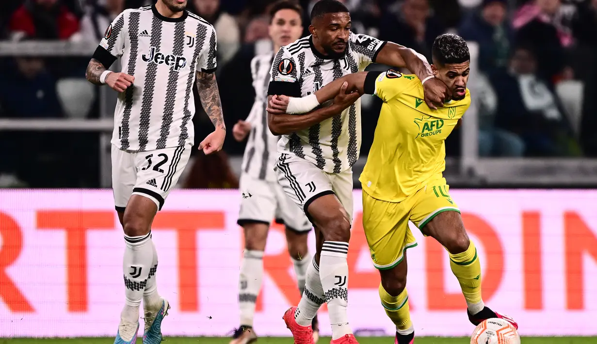 Bek Juventus Bremer (Tengah) menahan gelandang antes Ludovic Blas dalam duel leg pertama play-off babak gugur Liga Europa 2022/2023 di Allianz Stadium, Jumat (17/2/2023) dini hari WIB. Hasil imbang 1-1 ini terbilang bagus bagi Nantes yang bakal meladeni Juve di markas mereka dalam duel leg kedua pekan depan. (Marco BERTORELLO / AFP)