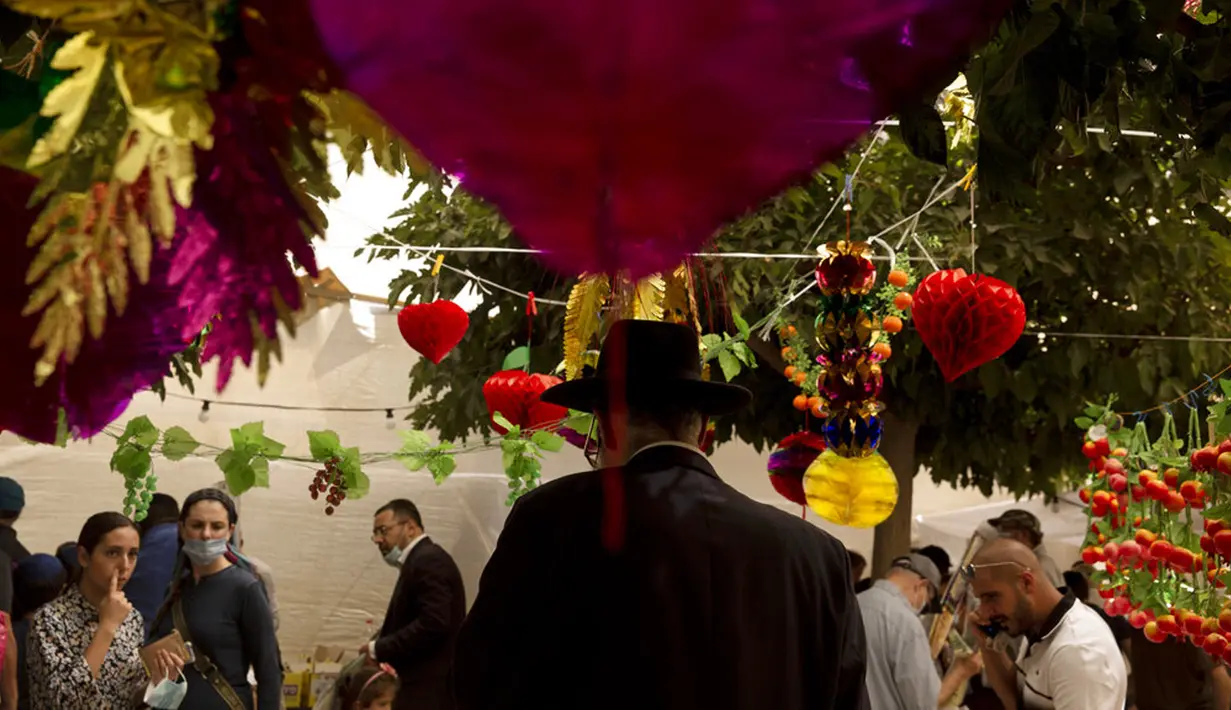 Umat Yahudi berbelanja barang-barang yang akan digunakan dalam ritual Hari Raya Sukkot di Yerusalem, 20 September 2021. Tenda tempat mereka berbelanja didirikan di seberang Pasar Mahane Yehuda yang diperuntukkan bagi pemegang Green Pass yang sudah divaksinasi COVID-19. (AP Photo/Maya Alleruzzo)