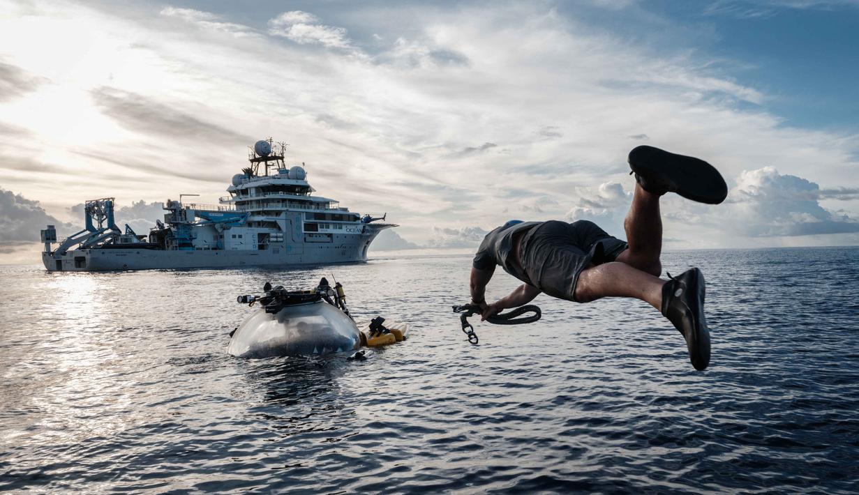 Menggunakan kapal selam Neptune milik organisasi nirlaba OceanX di perairan lepas pantai Pulau Sulawesi. Tampak dalam foto yang diambil pada 9 Januari 2026, menunjukkan awak kapal OceanXplorer, sebuah kapal penelitian yang dioperasikan oleh organisasi nirlaba kelautan OceanX, melompat ke laut dari sebuah perahu untuk berenang menuju kapal selam yang muncul ke permukaan dan memasang tali penyelamat di perairan lepas pantai Pulau Sulawesi. (YASUYOSHI CHIBA/AFP)