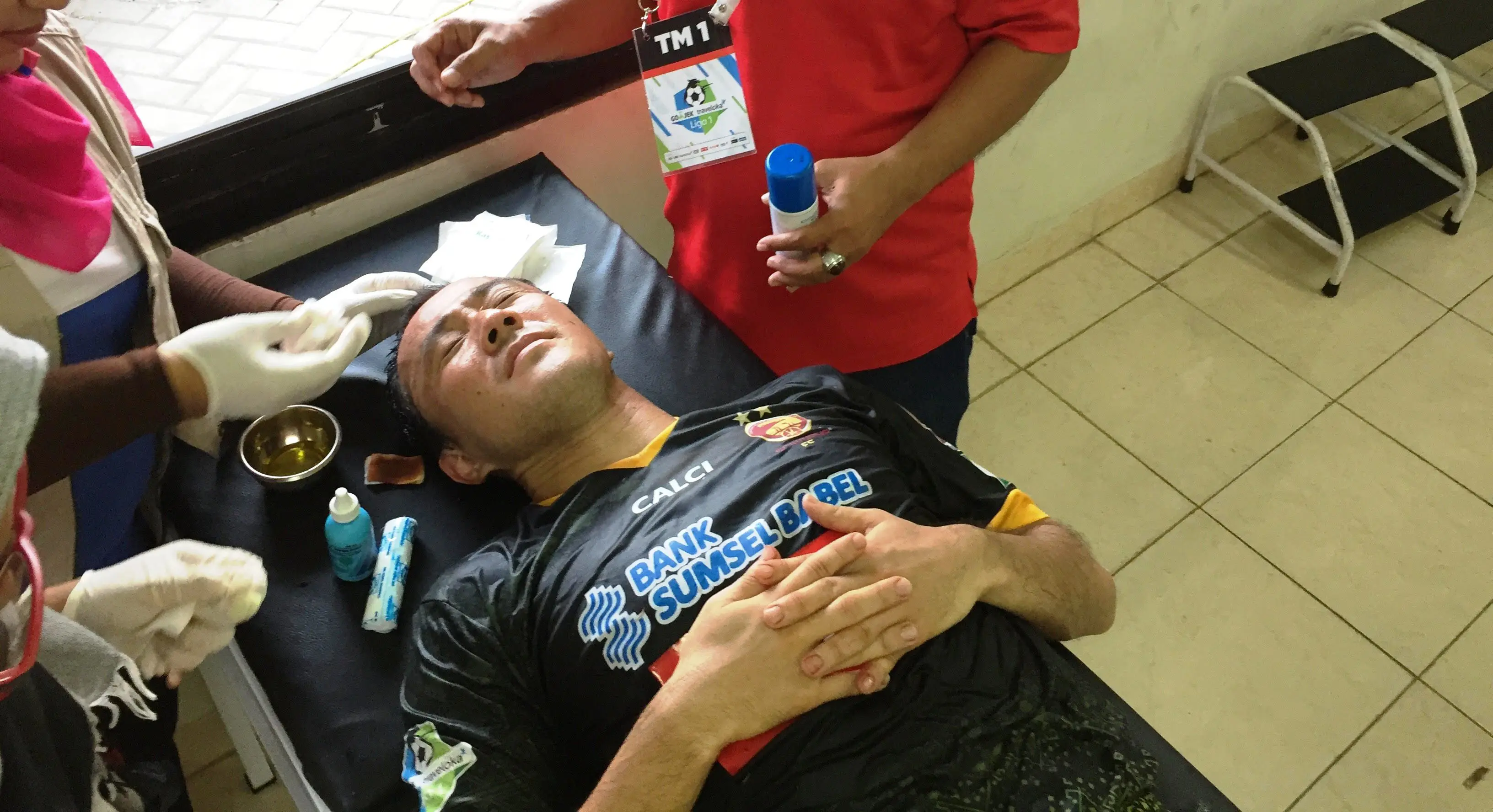 Gelandang Sriwijaya FC, Yu Hyun-koo, mendapat perawatan setelah mengalami cedera di kepala, Minggu (20/8/2017). (Bola.com/Riskha Prasetya)
