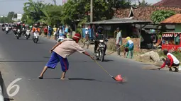 Penyapu jalan mengambil uang receh di kawasan Kabupaten Indramayu, Subang, Jawa Barat, Senin (11/7). Penyapu jalan atau yang di sebut Tawur sudah menjadi tradisi di jalur Pantura. (Liputan6.com/Herman Zakharia)