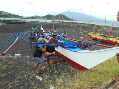 Warga dan nelayan membawa perahu kayu ke tempat yang lebih aman di sebuah desa di Kota Legaspi, provinsi Albay, selatan Manila, Filipina pada 16 November 2024. (CHARISM SAYAT/AFP)