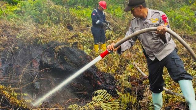 Polisi memadamkan kebakaran lahan di lahan semak beluka, Kecamatan Payung Sekaki, Kota Pekanbaru.