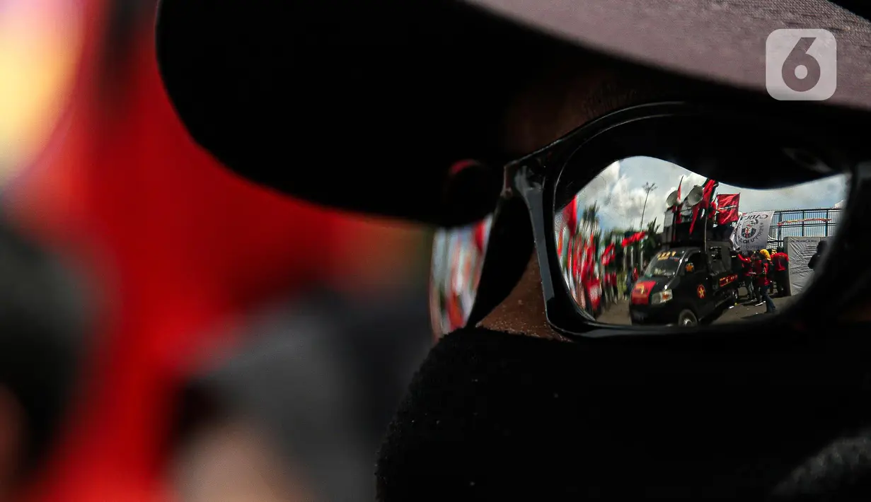 Aksi unjuk rasa buruh terefleksi dari kacamata massa yang menggeruduk gedung DPR RI, Jakarta, Selasa (10/1/2023). Dalam aksinya mereka menyuarakan penolakan terhadap Peraturan Pemerintah Pengganti Undang-Undang (Perppu) Cipta Kerja karena dinilai telah mengkhianati konstitusi. (Liputan6.com/Faizal Fanani)