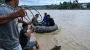 Pembangunan jembatan darurat sangat penting agar mobilitas masyarakat setempat dapat kembali berlangsung dengan normal. Tampak dalam foto, warga menggunakan ban dalam sebagai perahu darurat untuk menyeberangi sungai setelah jembatan rusak akibat banjir di Juli, provinsi Aceh, pada Minggu 14 Desember 2025. (CHAIDEER MAHYUDDIN/AFP)
