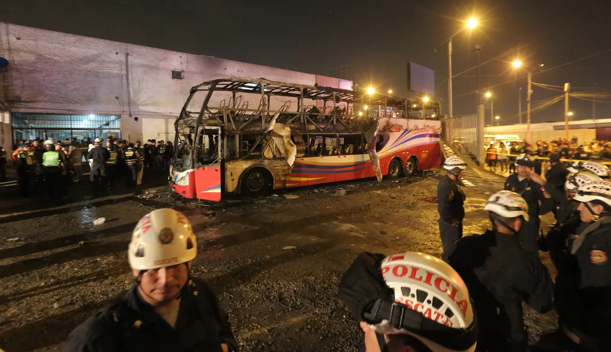 Petugas kepolisian berdiri dekat kerangka  bus bertingkat yang hangus terbakar di terminal bus antarprovinsi, kota Lima, Peru, Minggu (31/3). Pihak berwenang masih menyelidiki penyebab pasti mengapa bus yang penuh penumpang itu ludes dilalap api. (Photo by Luka GONZALES / AFP)