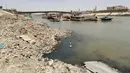 Kapal feri kayu ditambatkan di sepanjang tepi kanan sungai Tigris dekat jembatan al-Ahrar (Latar Belakang) saat permukaan air sungai semakin dangkal, di pusat ibu kota Irak, Baghdad, pada 26 Mei 2022. Bank Dunia memperkirakan bahwa tanpa perubahan besar, Irak akan kehilangan 20 persen sumber daya airnya pada tahun 2050. (AHMAD AL-RUBAYE/AFP)