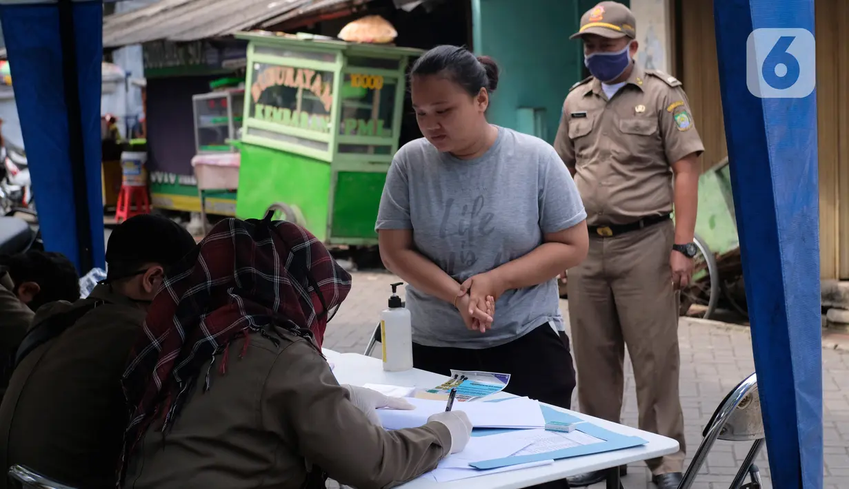 Petugas mendata seorang perempuan yang tidak mengenakan masker di Tangerang, Kamis (14/5/2020). Pemkot Tangerang melakukan tindakan bagi pelanggar PSBB dengan membawa mereka ke kantor Kecamatan Karawaci Baru untuk dilakukan pemeriksaan cepat COVID-19 (Rapid Test). (Liputan6.com/Angga Yuniar)