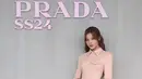 Sana Twice hadir di fashion show Prada mengenakan dress bodycon pink berkerah sambil membawa handbag putih serasi dengan heelsnya. [@prada]