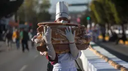 Siswa gastronomi ikut serta memecahkan Guinness World Record dengan membuat kue raja terpanjang di dunia, di Saltillo, Meksiko, 6 Januari 2019. Acara ini juga digelar sebagai pesta tahunan Epiphany di kota tersebut. (Julio Cesar AGUILAR/AFP)