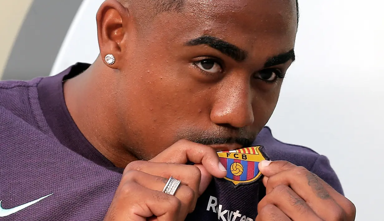 Pesepakbola muda Brasil, Malcom Filipe Silva de Oliveira mencium jersey berlogo Barcelona setibanya di stadion Camp Nou, Selasa (24/7). Winger berusia 21 tahun itu siap memberikan kegembiraan kepada publik Camp Nou. (AP Photo/Manu Fernandez)