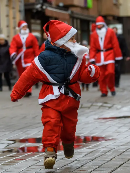 Seorang anak mengenakan kostum Sinterklas ikut serta dalam kegiatan amal Santa's Fun Run di Riga, Latvia, Minggu (8/12/2019). Ini merupakan acara amal yang pesertanya bersenang-senang dengan berlari atau berjalan kaki untuk mengumpulkan dana bagi anak-anak di rumah sakit Latvia. (Gints Ivuskans/AFP)