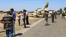 Sejumlah warga melihat kondisi pesawat jet tempur Libya L-39 Albatros pasukan Khalifa Haftar di Kota Medenine di perbatasan Tunisia-Libya (22/7/2019). Jet tempur tersebut mendarat di jalan raya. (AFP Photo/Fathi Nasri)