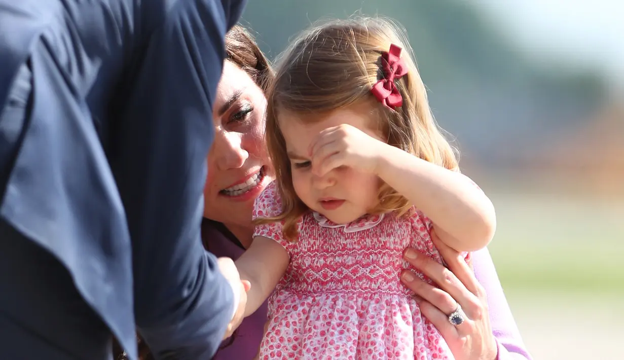 Kate Middleton membujuk anaknya, Putri Charlotte saat mengunjungi Pabrik Airbus di Hamburg, Jerman, 21 Juli 2017. Charlotte tertangkap kamera sedang merajuk dan enggan naik helikopter di pabrik pesawat terbang itu. (Christian Charisius/Pool Photo via AP)