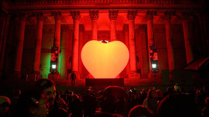 Masyarakat mengagumi instalasi seni bercahaya bertajuk 'With Love ...'  karya seniman Prancis Franck Pelletier  yang diproyeksikan di Balai Kota Leeds, utara Inggris, 10 Oktober 2019. Festival tersebut menampilkan proyeksi, instalasi interaktif, eksebisi, dansa, dan musik. (Oli SCARFF/AFP)