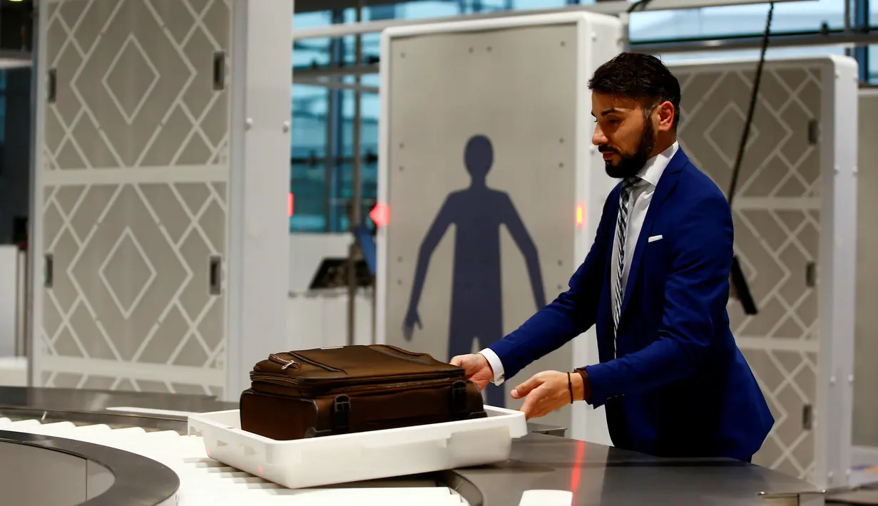 Petugas saat memasukkan tas penumpang ke mesin deteksi di Bandara Cologne-Bonn Konrad Adenaue, Jerman (15/11). Mesin ini akan secara otomatis mendeteksi benda-benda yang berpotensi bahaya. (REUTERS/Wolfgang Rattay)