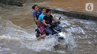Pengendara motor melintasi banjir di Jalan Benteng,  Duta Kranji, Kalibaru, Bekasi, Jawa Barat, Jumat (24/2/2023). Jalan yang dilalui oleh para pengendara masih digenangi air ditambah dari luapan kalibaru Duta Kranji akibat hujan deras yang mengguyur Kota Bekasi sejak Kamis (23/2/2023) malam. (merdeka.com/Imam Buhori)
