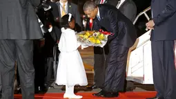 Presiden AS, Barack Obama menerima bunga dari seorang anak saat di bandara intenasional Kenyatta, Nairobi, Kenya, (24/7/2015). Ratusan orang berbaris menyambut Presiden Obama Jr saat kedatangan pertamanya ke Kenya. (REUTERS/Jonathan Ernst)