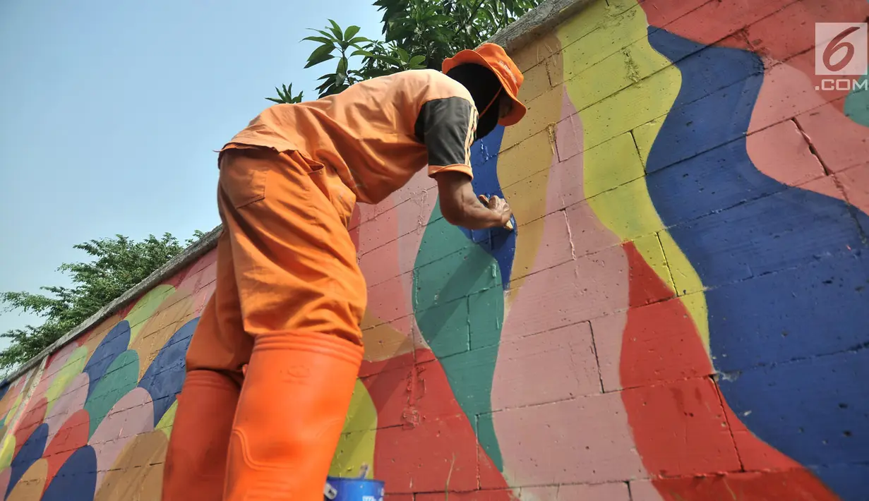 Petugas PPSU mengecat saat pembuatan mural pada tembok yang berada di pinggir Jalan Landasan Pacu, Jakarta, Rabu (11/7). Pengecatan dan pembuatan mural ini dalam rangka mempercantik kawasan serta menyambut Asian Games 2018. (Merdeka.com/Iqbal S. Nugroho)