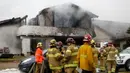 Petugas pemadam kebakaran berusaha memadamkan api di lokasi kecelakaan pesawat di sebuah rumah di Yorba Linda, California (3/2). (AP Photo/Alex Gallardo)