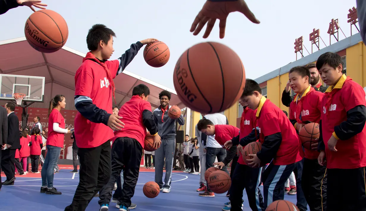 Pemain New Orleans Pelicans, Shawn Dawson mengajarkan para siswa bermain basket dalam acara amal di Sekolah Migran Huangzhuang, Beijing, Tiongkok (11/10). (AP Photo/Ng Han Guan)