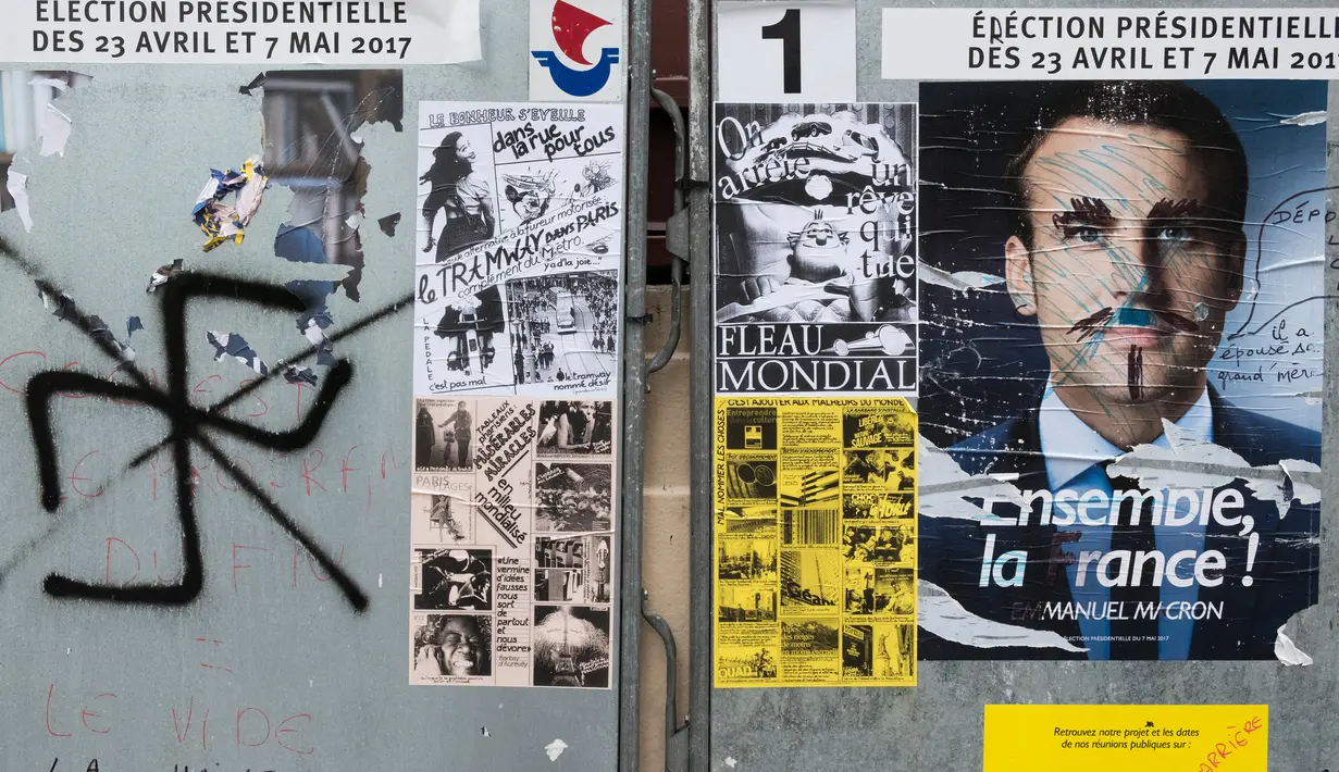 Poster salah satu Capres Prancis terkena aksi vandalisme di Paris, Selasa (2/5). Sejumlah poster capres Prancis lainnya juga tampak rusak yang diduga dilakukan oleh orang yang tidak suka dengan mereka. (AFP PHOTO / JOEL SAGET)