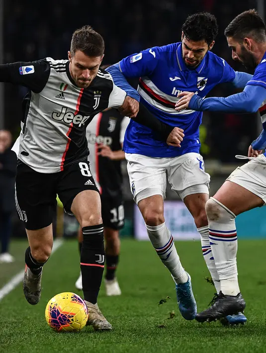 Gelandang  Juventus, Aaron Ramsey (kiri) membawa bola dari kawalan pemain Sampdoria, Mehdi Leris dan Nicola Murru pada pertandingan lanjutan Liga Serie A Italia di stadion Luigi-Ferraris di Genoa (18/12/2019). Juventus menang tipis 2-1 atas Sampdoria. (AFP/Marco Bertorello)