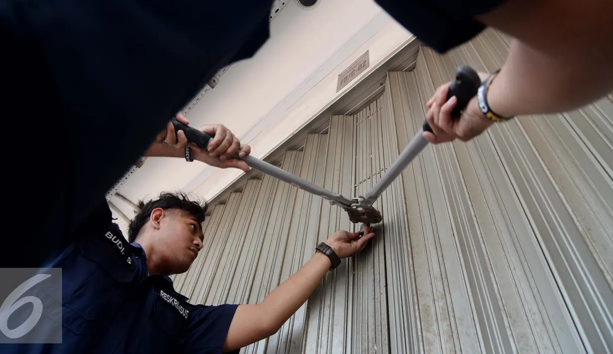 Petugas berusaha membuka pintu ruko di Graha Bintaro, Tangerang Selatan, Kamis (18/2). Penyegelan dua ruko merupakan hasil pengembangan penangkapan 7 orang tersangka dengan modus kejahatan penipuan online. (Liputan6.com/Faisal R Syam)